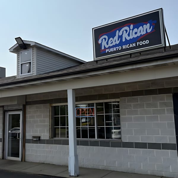 Exterior of Red Rican restaurant with a large sign and an "OPEN" neon sign in the window.