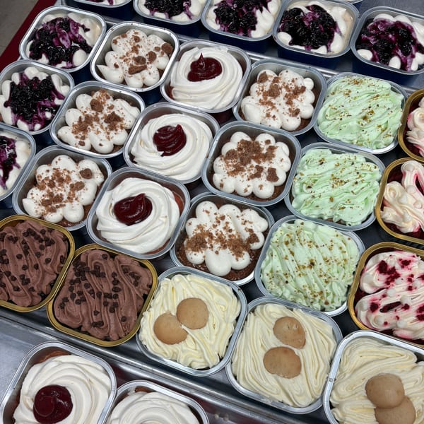 An overhead view of various Red Rican desserts in foil containers, including blueberry, chocolate, and pistachio.
